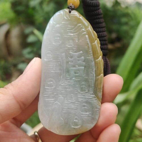 a hand holding a jade pendant