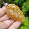 a hand holding a yellow stone pendant