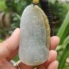 a hand holding a jade pendant