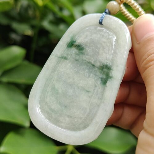 a hand holding a jade pendant