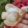 a hand holding a stone fish pendant