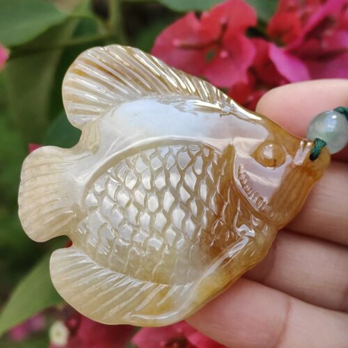 a hand holding a stone fish pendant