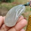 a hand holding a jade pendant