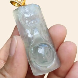 a hand holding a jade pendant