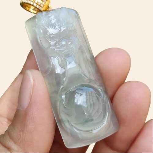 a hand holding a jade pendant