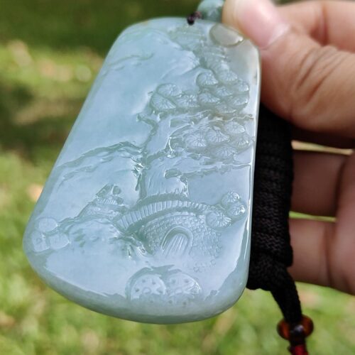 a hand holding a jade pendant