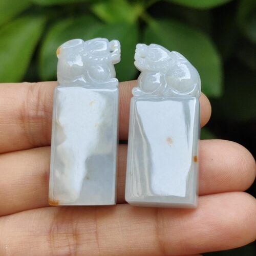 a hand holding a pair of carved stone animals