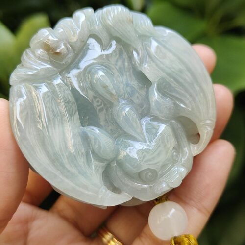 une main tenant un pendentif en jade