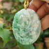a hand holding a jade pendant