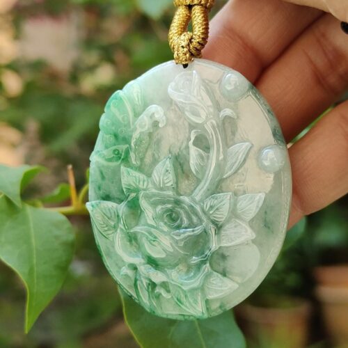 a hand holding a jade pendant