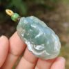 a hand holding a jade pendant