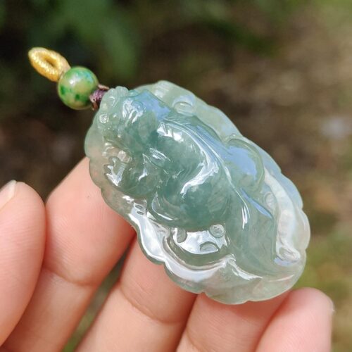 a hand holding a jade pendant