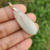 a hand holding a white pendant