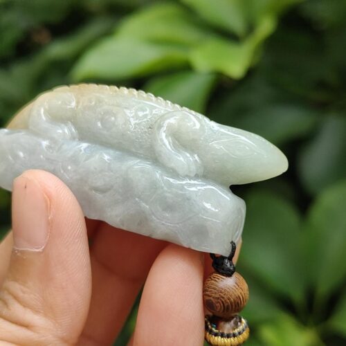 a hand holding a jade pendant