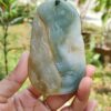 a hand holding a jade pendant