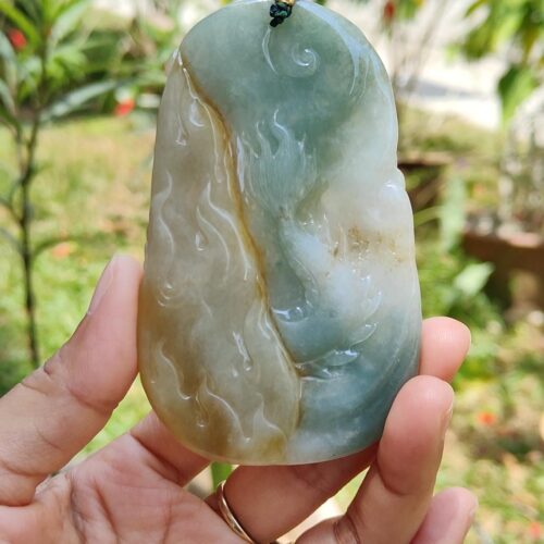 a hand holding a jade pendant