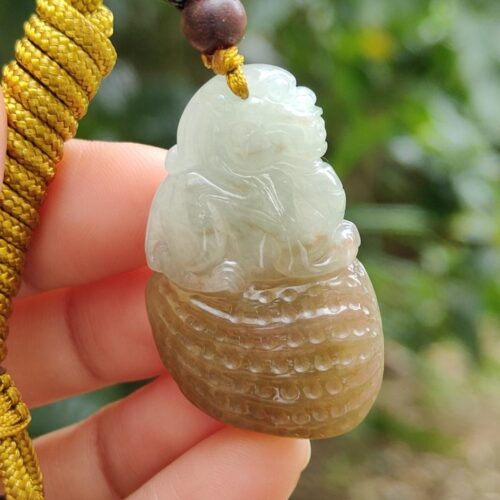 une main tenant un pendentif en jade