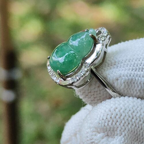 a hand wearing a white glove with a green stone ring