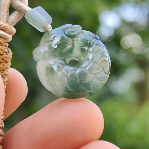 a hand holding a jade pendant