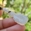 Una mano sosteniendo un colgante de jade blanco.