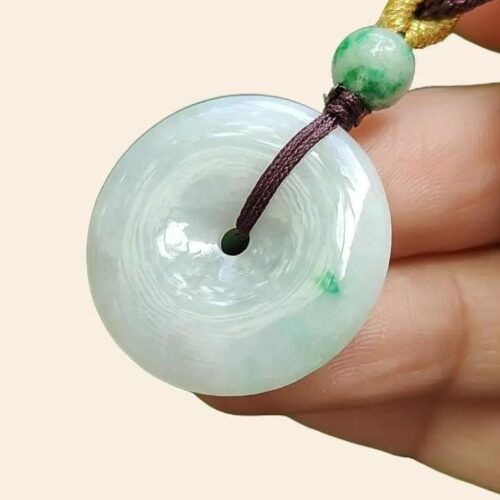 une main tenant un pendentif en jade