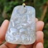 a hand holding a jade pendant