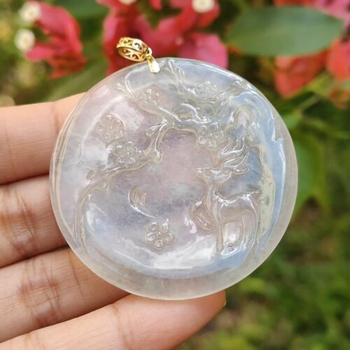 a hand holding a round white stone pendant