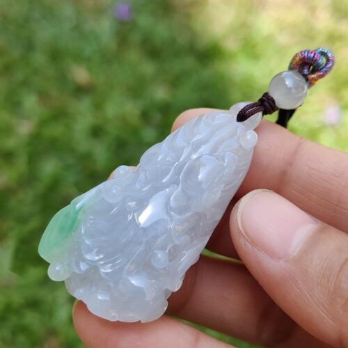 Una mano sosteniendo un colgante de jade.