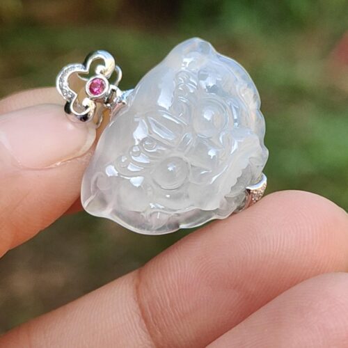 a hand holding a white jade pendant
