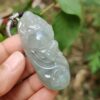 une main tenant un pendentif en jade