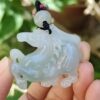 a hand holding a jade horse pendant