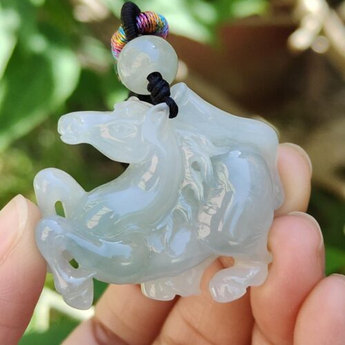 a hand holding a jade horse pendant