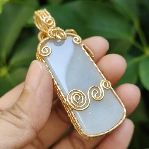 एक हाथ में पेंडेंट पकड़े हुए