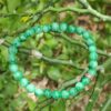 a green beaded bracelet on a branch