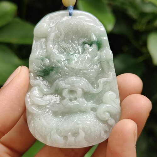 a hand holding a jade pendant