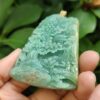 a hand holding a jade pendant