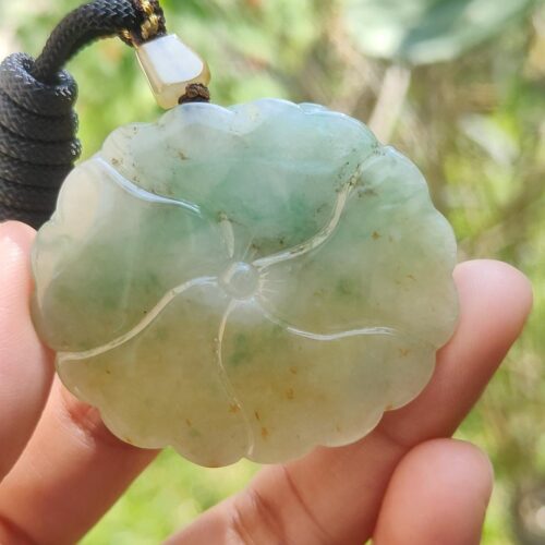 a hand holding a jade pendant