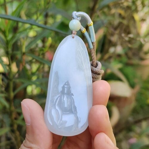 a hand holding a jade pendant