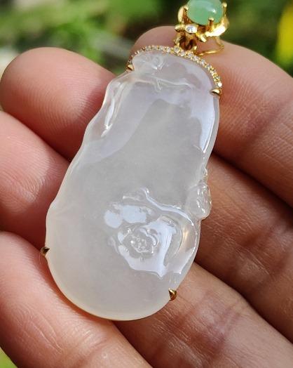 a hand holding a jade pendant