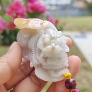 a hand holding a small white stone dragon