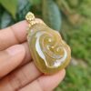 a hand holding a jade pendant