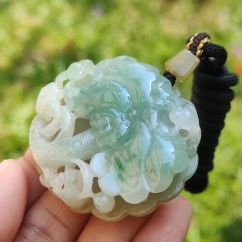 a hand holding a jade pendant