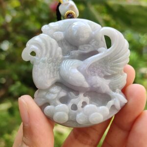 a hand holding a jade pendant