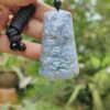 a hand holding a blue and white jade pendant