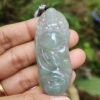une main tenant un pendentif en jade
