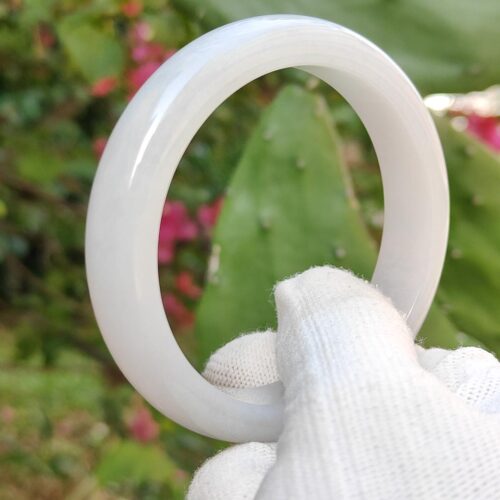 a hand in glove holding a white ring