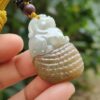 une main tenant un pendentif en jade