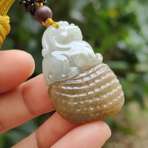 une main tenant un pendentif en jade