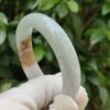 a hand holding a white gloved hand holding a round white bracelet