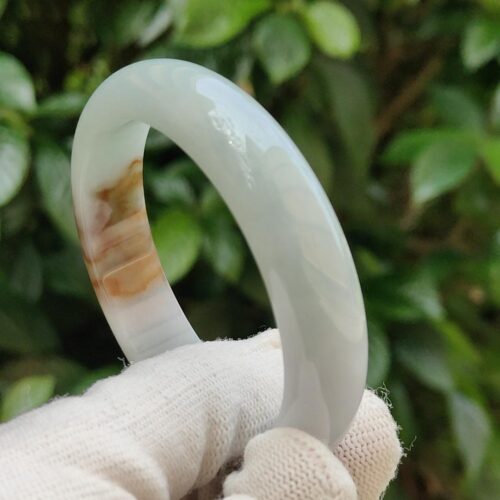 a hand holding a white gloved hand holding a round white bracelet